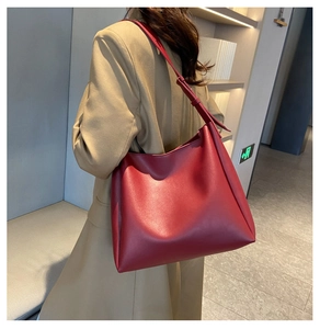 Deep burgundy leather tote bag styled on model over the shoulder in minimalist setting