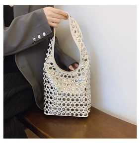 Détail du sac hobo en cuir blanc avec clous métalliques argentés tenu par un mannequin