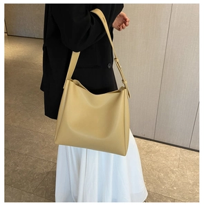Detailed side view of ginger yellow leather tote bag with wide strap on model