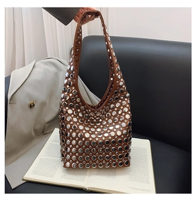 Détail du sac seau en cuir marron orné de rivets argentés denses au style punk et chic