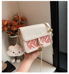 Detail of crossbody bag with pink woven texture, chain strap and cloud charm