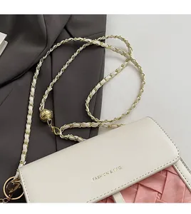 Detailed macro view of cream PU leather crossbody bag featuring gold chain with ball adjuster