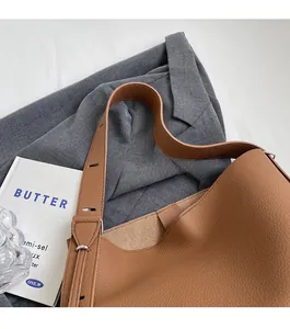 Detail of tan pebble leather bucket bag featuring an adjustable wide shoulder strap