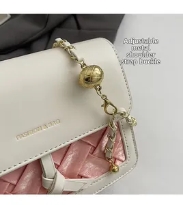Detail of adjustable gold ball chain buckle and woven cream leather on the shoulder bag