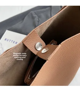 Close-up of brown lychee leather bucket bag showing magnetic clasp and zip pocket