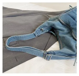 Detail of adjustable strap with silver buckle on blue denim crossbody bag