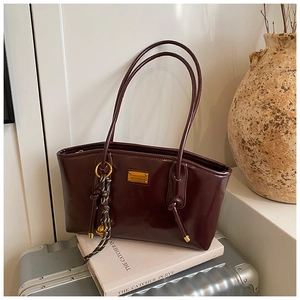 Detailed close-up of glossy wine red shoulder bag on a metallic suitcase