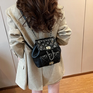 Quilted black leather backpack with gold chain straps and twist-lock on a beige blazer