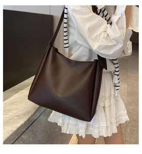 Side view of large coffee brown matte leather tote bag on model for daily commuting use