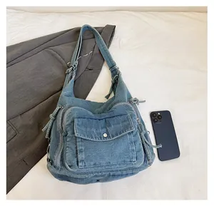 Flat lay of blue denim tote bag with multiple pockets next to a smartphone for size reference