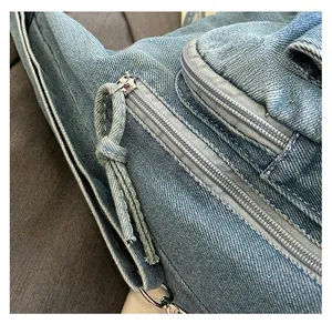 Detail of smooth metal zipper and light blue washed denim fabric on the backpack