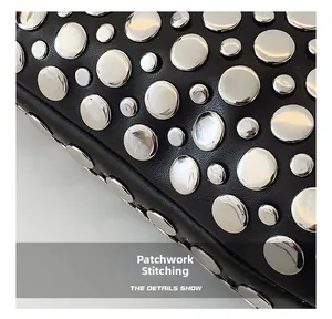 Détail des coutures du cuir et des rivets argentés sur un sac à main noir tendance