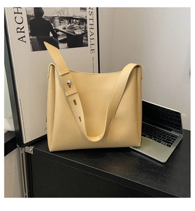 Close-up of minimalist beige leather tote bag with wide strap and silver metal rivets