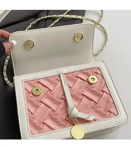 Detail of pink woven fabric and white leather handbag with golden magnetic clasp