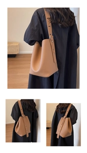 Detailed close-up of brown leather bucket bag showing grain texture and wide shoulder strap