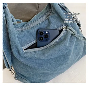 Front zipper pocket of blue denim tote bag showing a smartphone for storage capacity