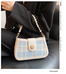 Detail of tweed shoulder bag featuring a pearl bead handle and wooden decorative buckle