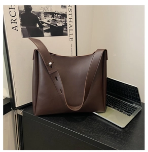 Detail of dark brown leather tote bag showing adjustable wide strap and smooth texture