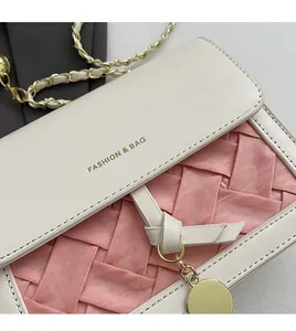 Close-up of pink woven fabric and white leather flap with gold logo and chain strap