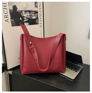 Detail of burgundy tote bag showing matte leather texture and silver buckle on wide strap