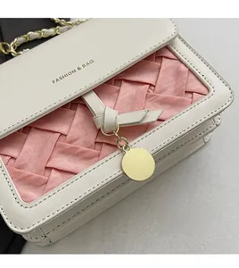 Detailed macro of the cream leather texture and pink woven fabric on this square bag