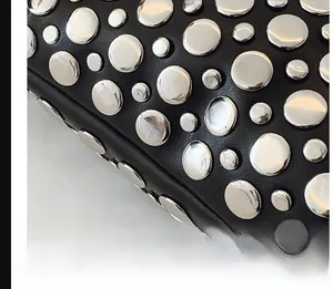 Détail du cuir grainé noir avec rivets argentés et surpiqûres professionnelles