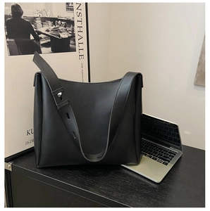 Detail of adjustable shoulder strap with silver eyelets on a black faux leather tote bag