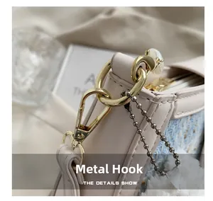 Macro detail of polished gold hardware hook and beaded chain on tweed crossbody bag