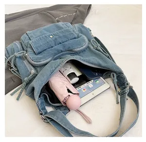 Detail view of denim backpack showing large internal capacity with various items