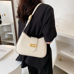 Minimalist beige half-moon baguette shoulder bag with gold buckle on a stylish model