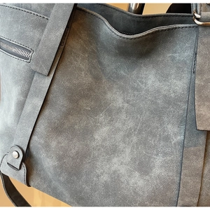 Gros plan du sac cabas vintage en cuir dépoli gris foncé avec rivets et détails zippés
