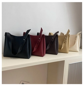 Detailed side view of five minimalist leather tote bags with accordion pleats and wide straps