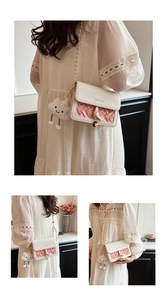 Detail of cream crossbody bag featuring pink woven texture and cloud charm attachment
