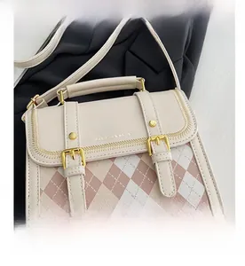 Detailed macro view of the cream and pink diamond pattern leather bag with gold buckle