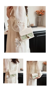 Detail of cream crossbody bag with woven texture, gold chain and cloud charm
