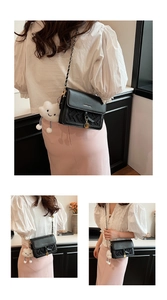 Detail of black woven leather crossbody bag with metal chain strap and cloud charm