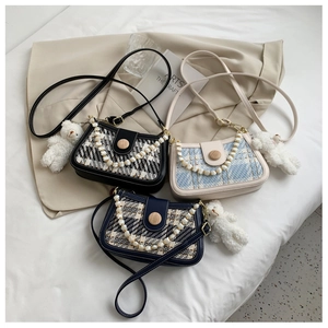 Detailed view of tweed crossbody bags with pearl handle and wooden buckle closures