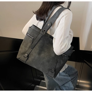 Sac cabas gris foncé vintage avec fermetures éclair porté à l'épaule en situation réelle