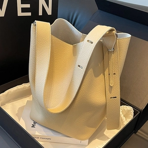 Minimalist beige lychee leather bucket bag with wide strap in an elegant black gift box