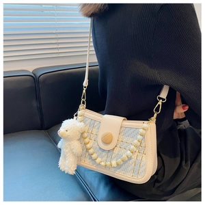 Detail of light blue tweed crossbody bag featuring a plush bear charm and pearl chain