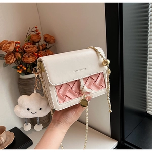 Detail view of woven leather texture and cloud charm on pink and beige crossbody bag