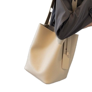 Beige lychee pattern leather bucket bag with top handle shown in a clean studio setting