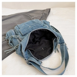 Detailed view of blue denim tote bag interior showing black lining and zip pocket