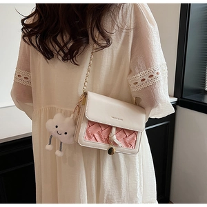 Detail of cream and pink woven leather crossbody bag with chain strap and cloud charm