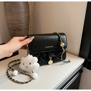 Detail of black leather bag with woven texture, metal chain, and cloud charm