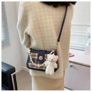 Detail of tweed crossbody bag with pearl strap, leather trim and bear charm accessory