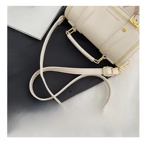 Detail of the adjustable slim leather shoulder strap on a beige cylinder fashion bag
