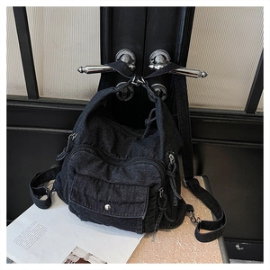 Detail of a vintage black denim backpack with multi-pocket design and silver hardware