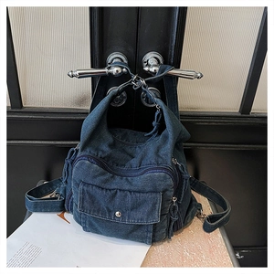 Detail of blue denim backpack with multi-zipper pockets and silver hardware closure