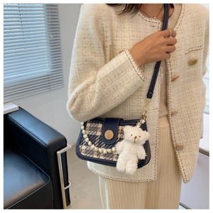 Detail of tweed mini crossbody bag with a pearl chain and a fluffy white bear charm